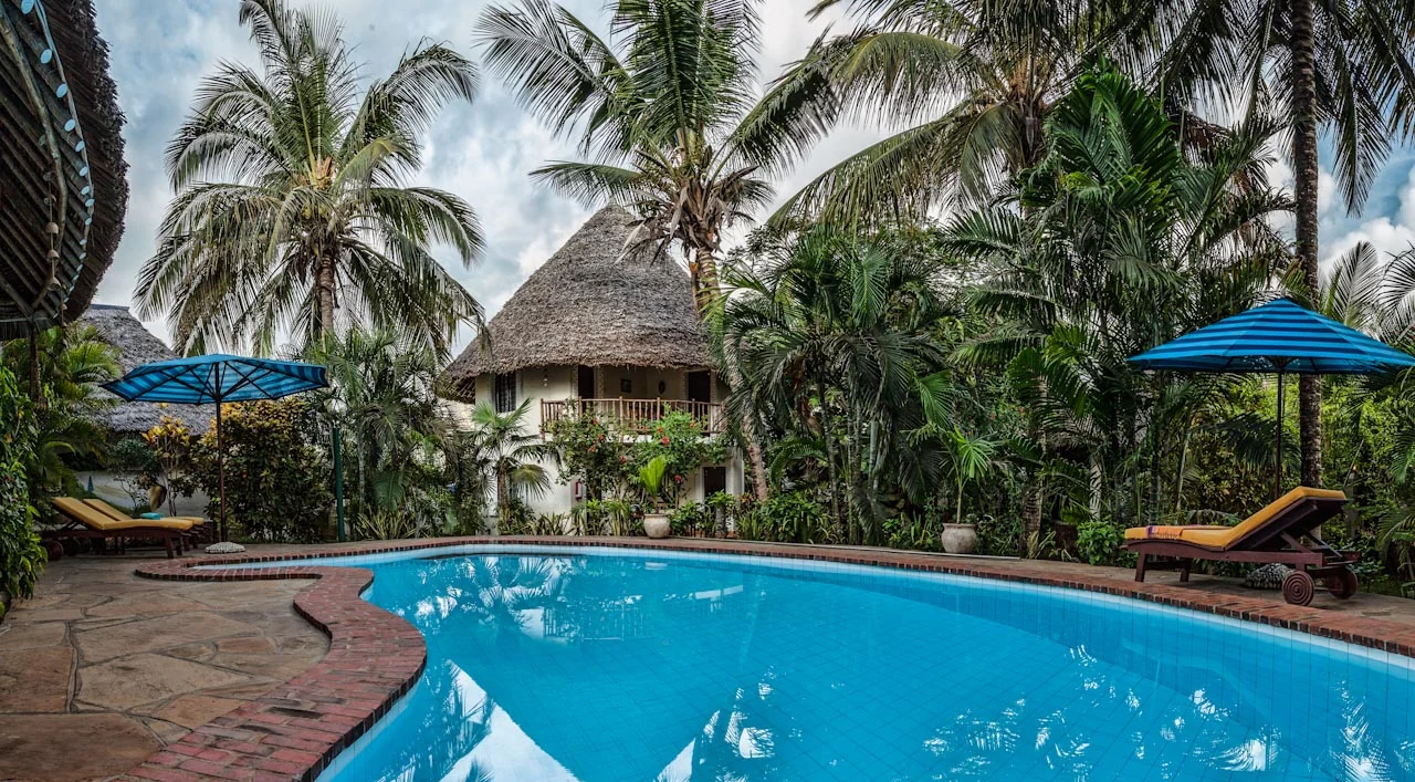 Pool framed by tall palms and thatched villa roof