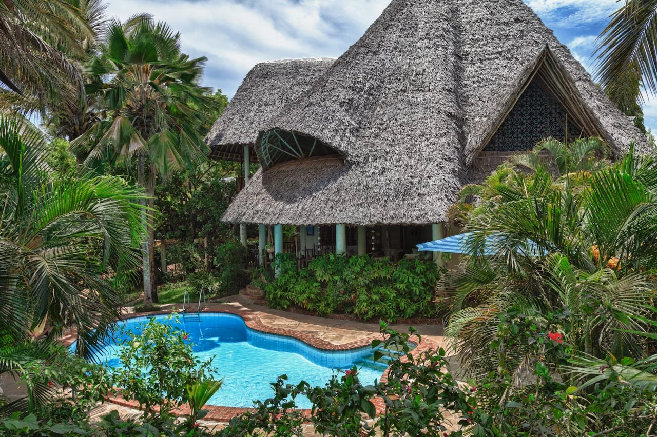 Thatched villa roof rising above the pool and palms