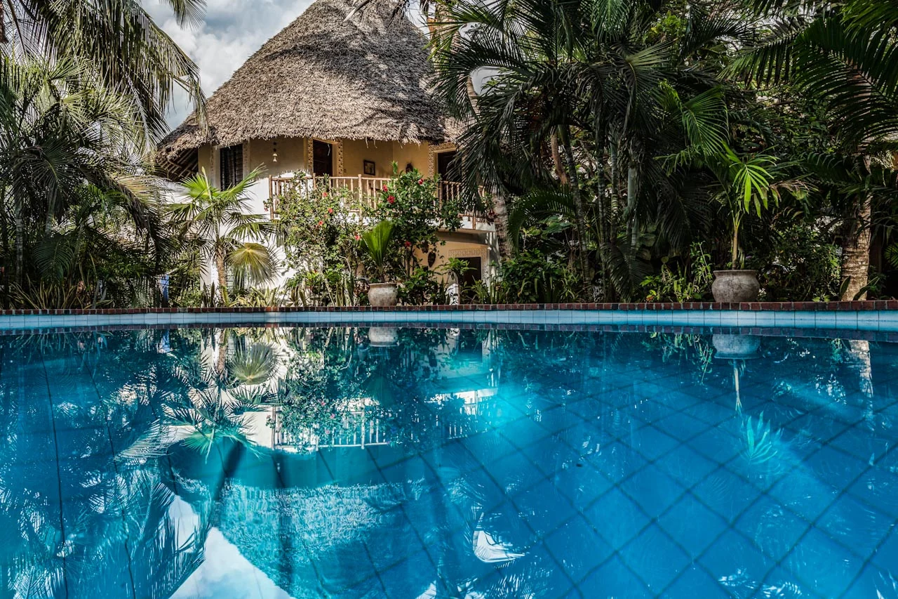 Villa reflected in the swimming pool through palms
